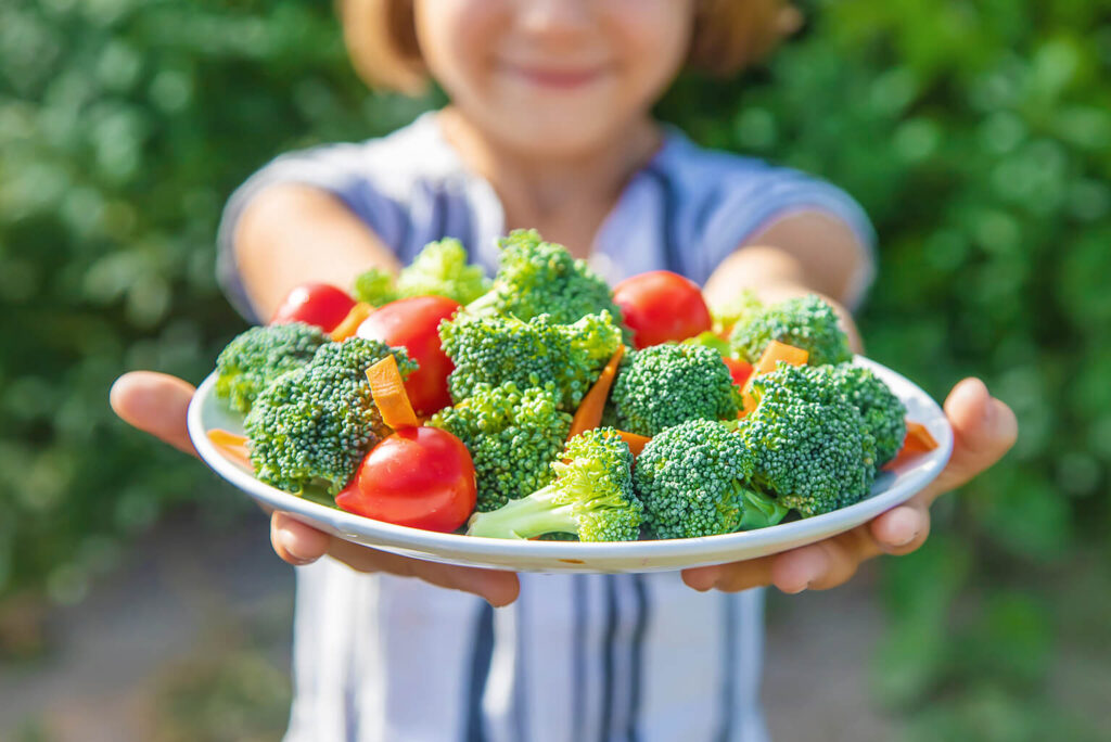 Young girl holding plate of vegetables